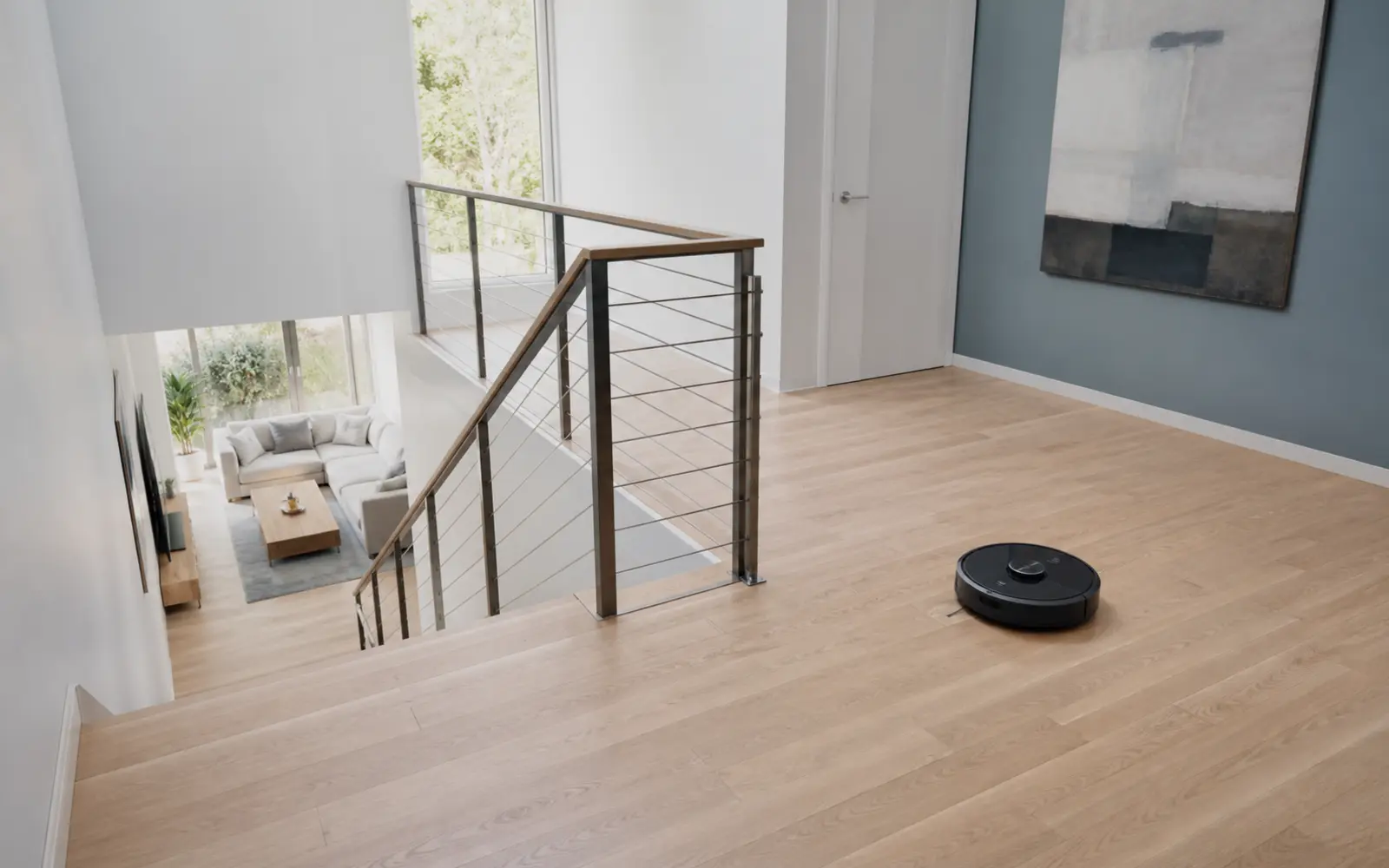Robot aspirador trabajando en el rellano superior de una vivienda de dos plantas, alejado de la escalera